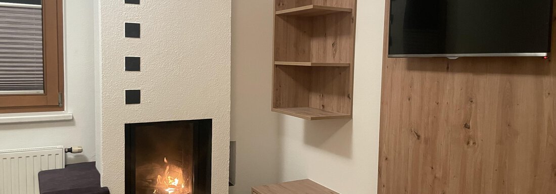 Ofen im Wohnzimmer mit Flat-TV - Apart Bergfee - Huben